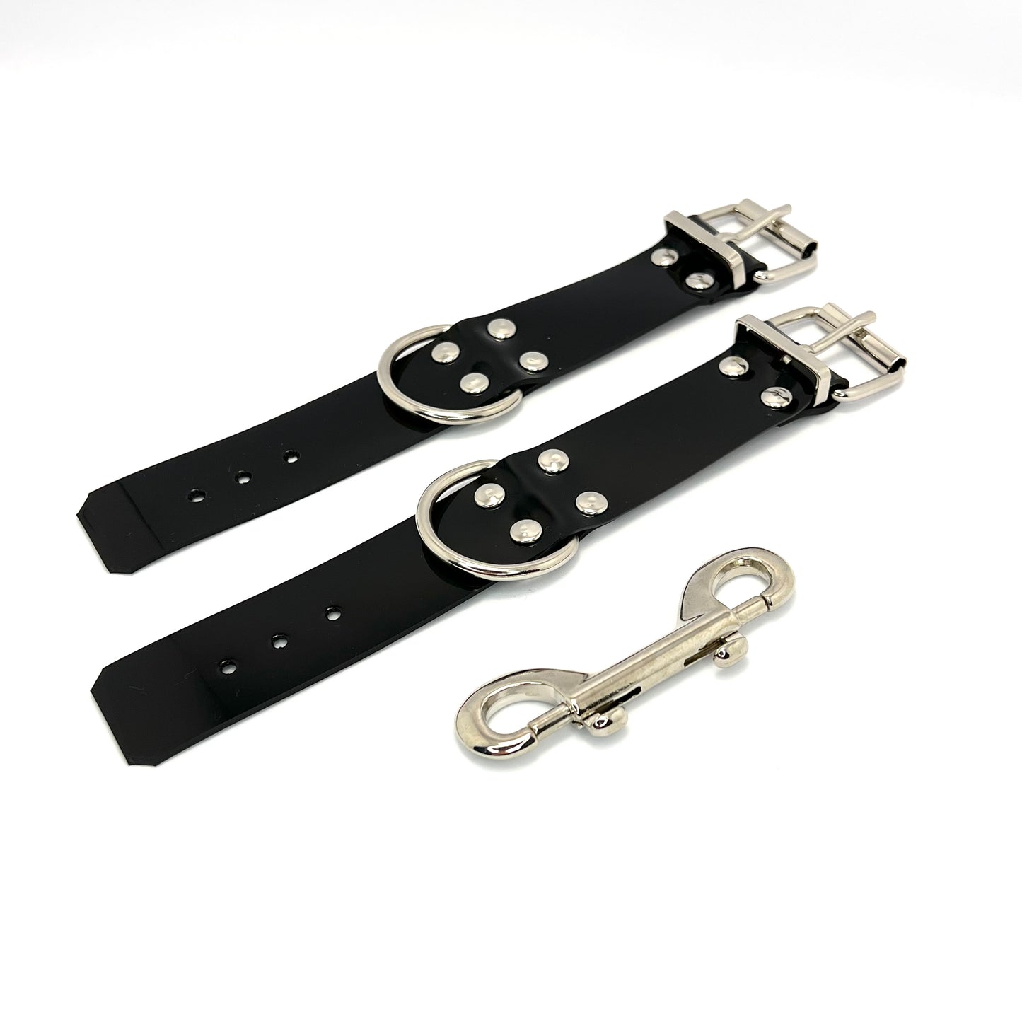 Black handcuffs layed out on a white background.