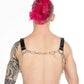 Tattooed man with a PVC chest harness back view
