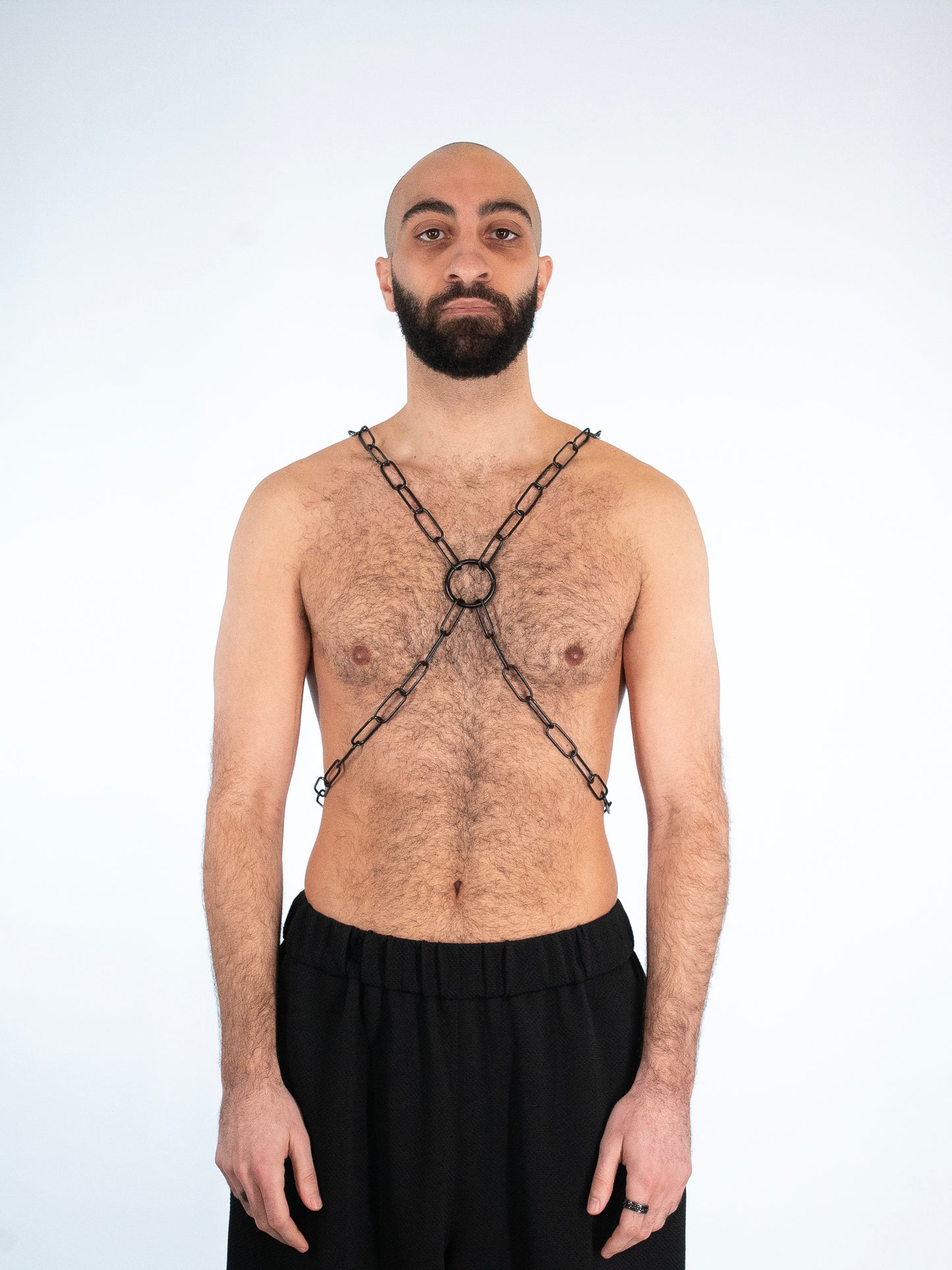 Front view of a man with beard wearing a black chain harness.