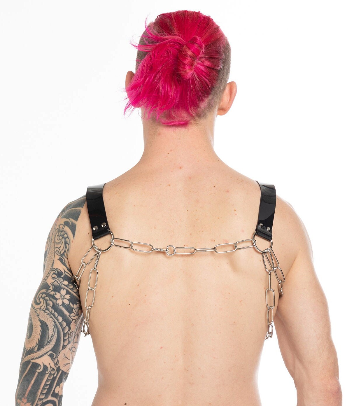 Tattooed man with a PVC chest harness back view